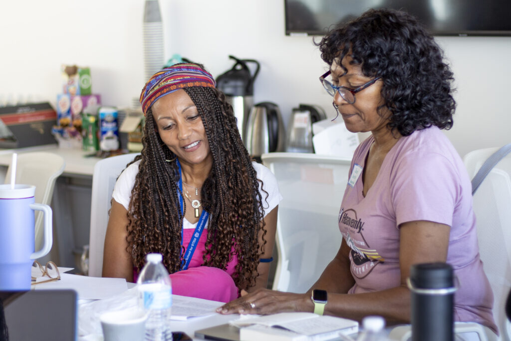 Two women sit and discuss material at a CRLP workshop.